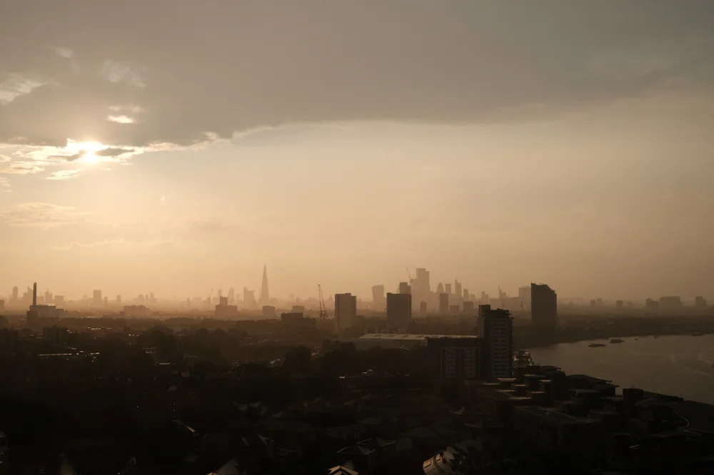 City buildings silhouetted beside a river at sunset