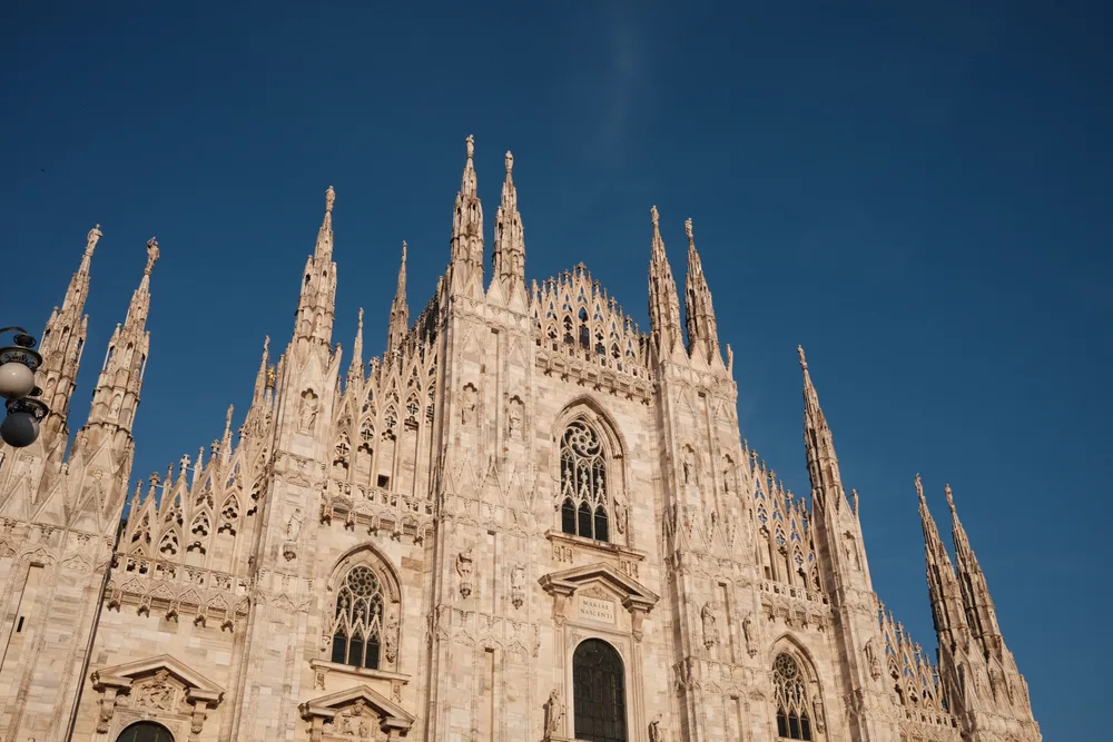 The ornate facade and Gothic spires of Milan Cathedral against a blue sky