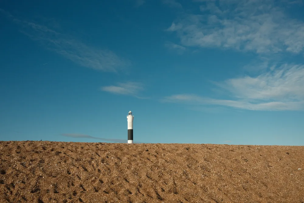 A black-and-white beacon behind a sandy mound