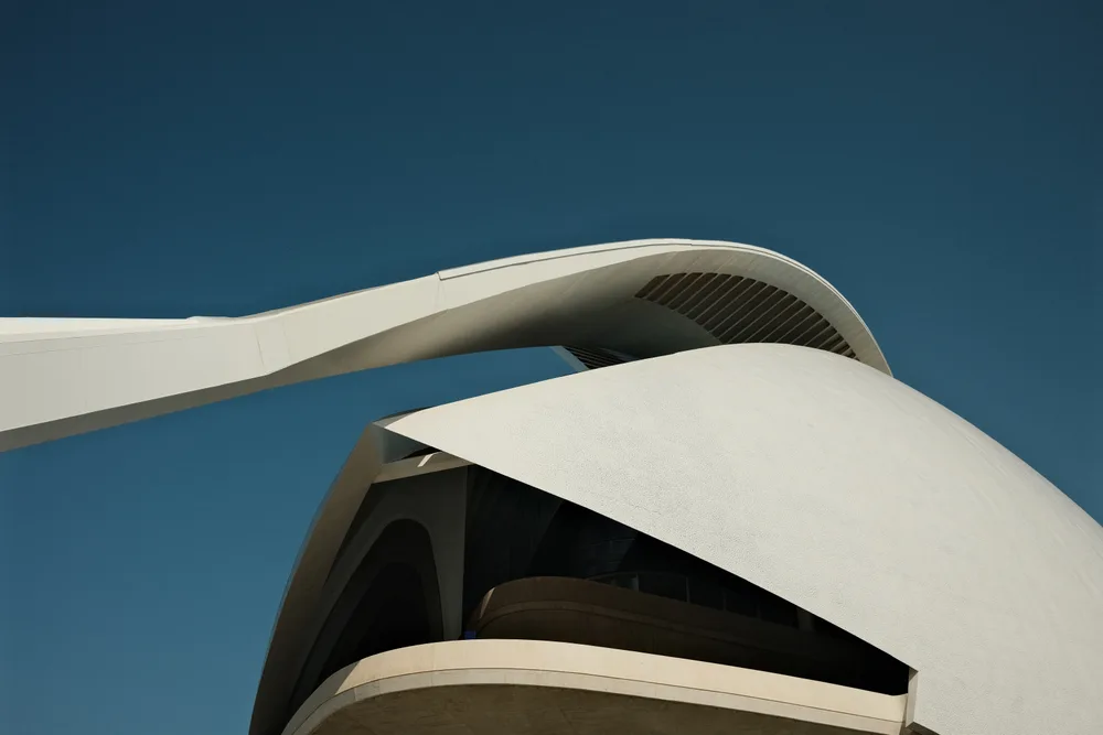 Curving white forms of a modern building against a deep blue sky
