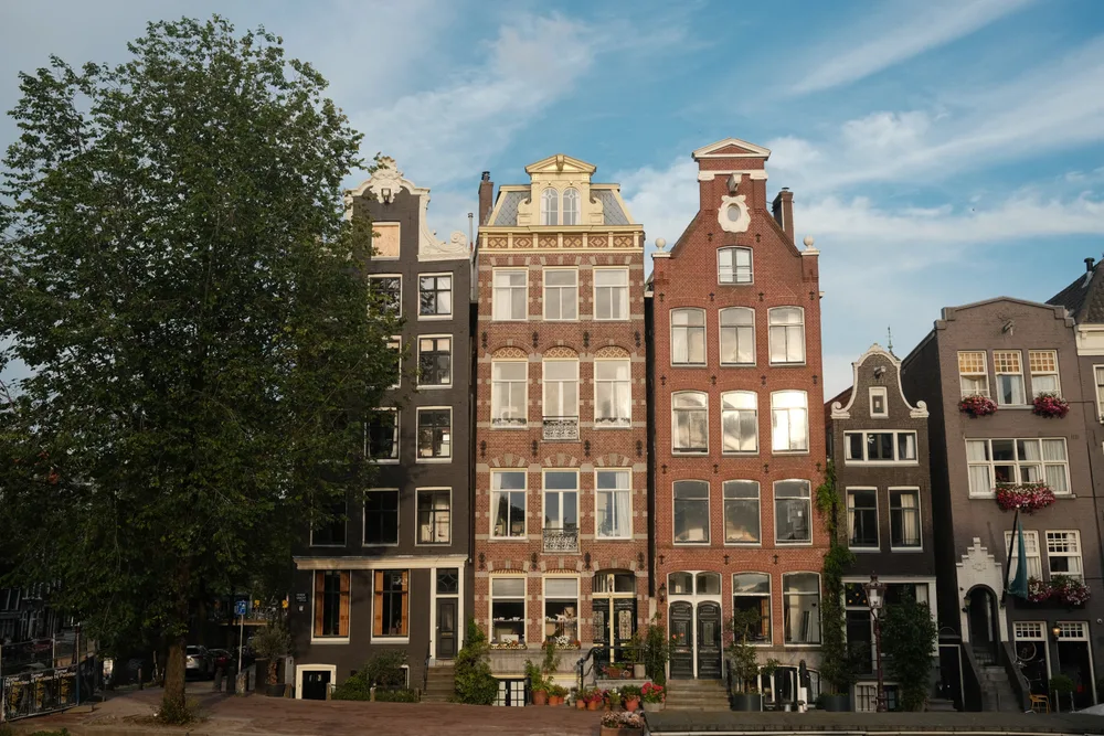 A row of narrow brick houses with decorative gables beside the water